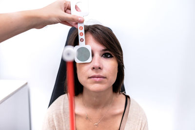 Unrecognizable female ophthalmologist using stick and checking vision of woman during appointment in modern clinic