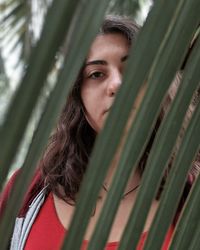 Portrait of young woman seen through palm leaves