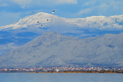 Scenic view of sea and snowcapped mountains against sky