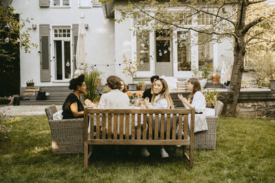 Portrait of smiling woman sitting with friends by table during garden party