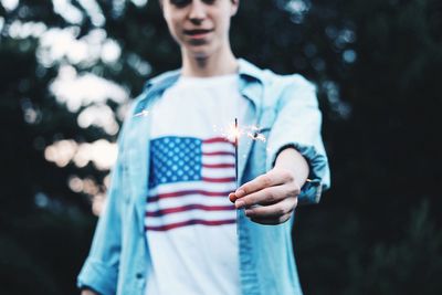 Midsection of boy holding lit sparkler