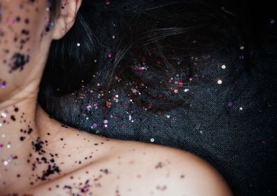 Cropped image of woman lying on carpet with glitter on skin