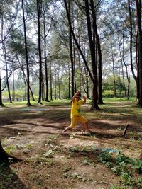 Side view of woman sitting on field in forest