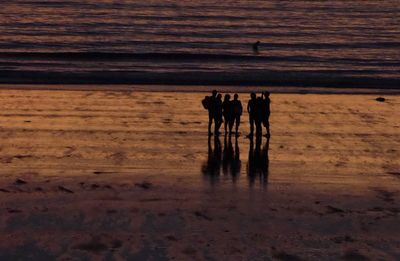 High angle view silhouette of people standing at sea shore