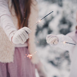 Midsection of sisters holding sparklers