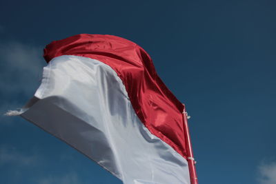 Low angle view of flag against blue sky