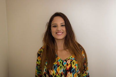 Portrait of woman with long brown hair against wall