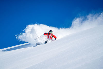 Woman skiing on snowcapped mountain against sky