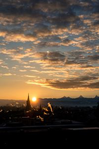 Cityscape against dramatic sky during sunset