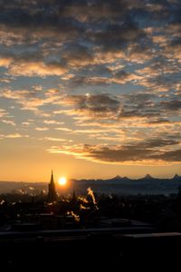 Cityscape against dramatic sky during sunset