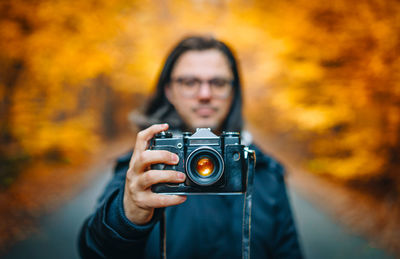 Photographer taking photos on autumn forest road
