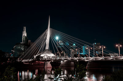 Illuminated bridge over river at night