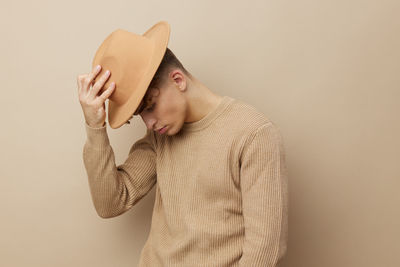 Side view of woman wearing hat standing against yellow background