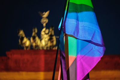 Rainbow flag against brandenburg gate in city at night