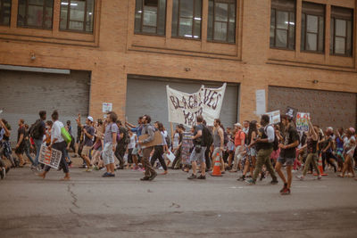 Protestors walking on city street against building