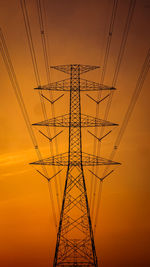 Low angle view of electricity pylon against sky during sunset