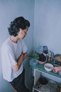 Side view of woman having food against wall at home