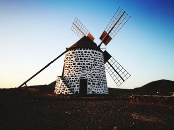 Traditional windmill on field against clear sky