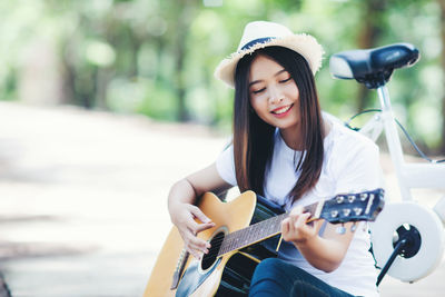 Portrait of a smiling young woman holding guitar