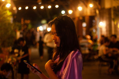 Side view of woman using mobile phone at night