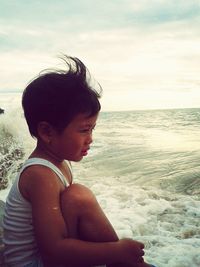 Boy on beach against sky during sunset