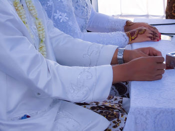 Midsection of bride and bridegroom sitting