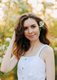 A cute happy young woman with a hairstyle in a white dress is walking enjoying nature in the summer