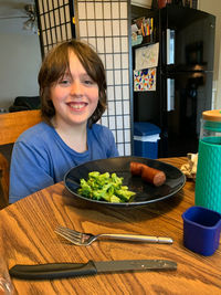 Smiling boy sitting at table with food