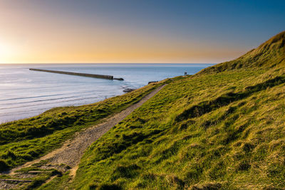 Couple enjoying elevated view of a ancient military pier just prior sunset at pointe de la crèche