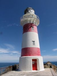 Lighthouse on shore against blue sky