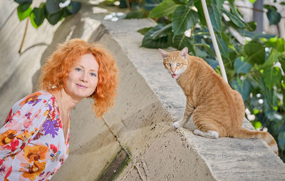 Portrait of woman with cat sitting outdoors