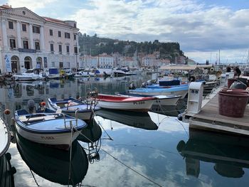 Boats moored at harbor against buildings in city