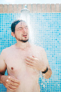 Full length of shirtless man in bathtub