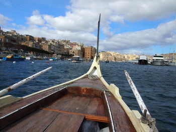 Sailboats moored on sea by buildings in city against sky