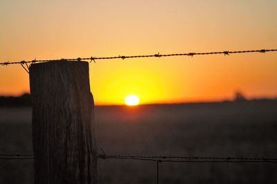 Silhouette of barbed wire against sky during sunset