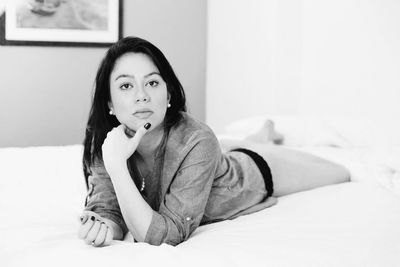 Portrait of woman sitting on bed at home