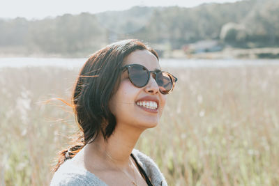 Portrait of young woman wearing sunglasses standing on field