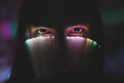 Close-up portrait of young woman holding illuminated fiber optic