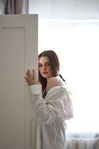 Young woman standing against white wall