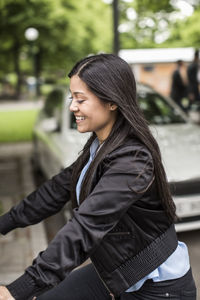 Side view of happy businesswoman riding bicycle