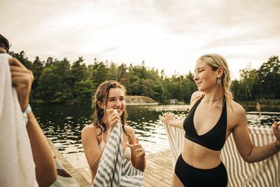 Women with towel talking to each other at lake during vacation