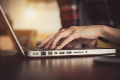 Close-up of person using laptop on table