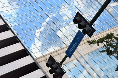 Low angle view of streetlight and modern building with sky reflection