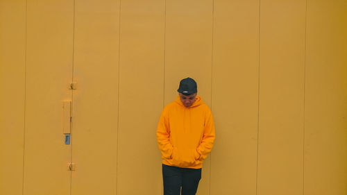 Young man standing against yellow wall