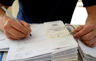 Midsection of man writing on document