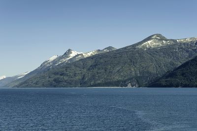 Scenic view of sea and mountains against clear blue sky