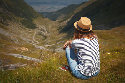 Rear view of woman sitting on mountain