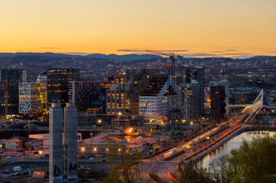 High angle view of illuminated cityscape against sky at sunset