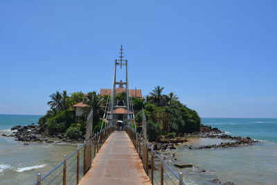 Pier over sea against clear blue sky