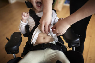 Parent taking care of disabled child in wheelchair at home